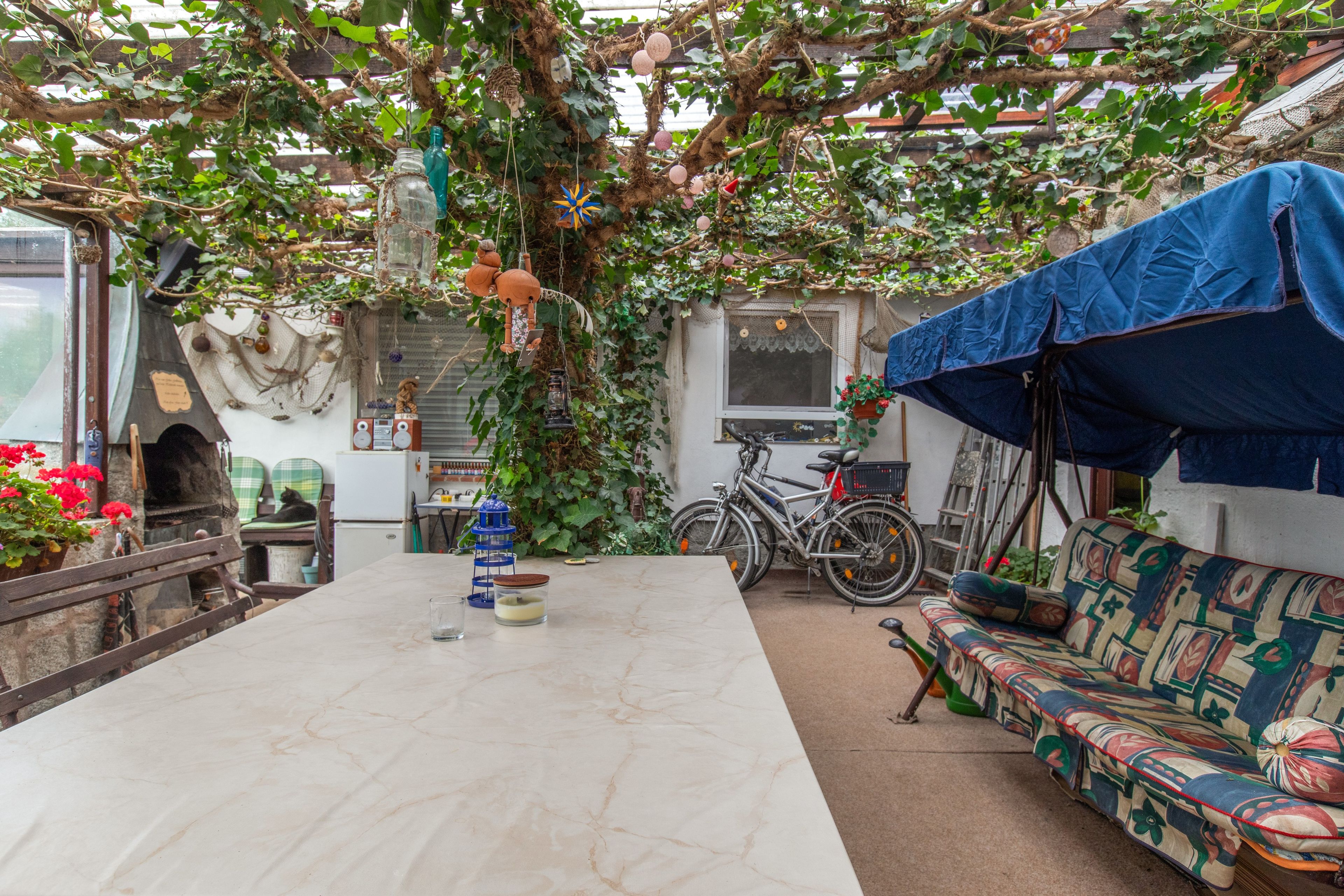 A rustic outdoor seating area with a table, a bicycle, and a covered bench.