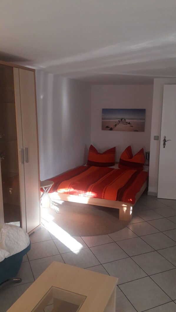 Une chambre à coucher avec un lit, une armoire, un tableau au mur et une porte.