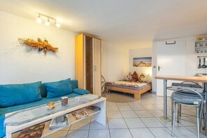 A compact living space with a sofa, a bed, a dining area, and a kitchenette.