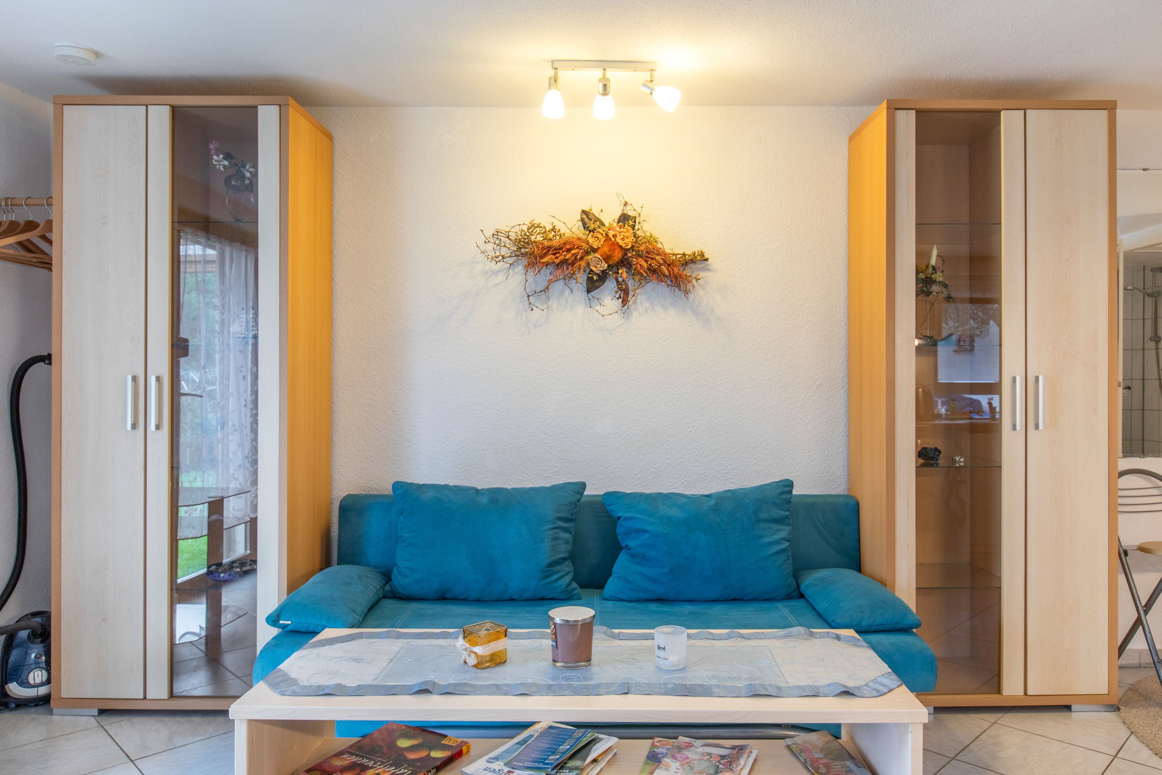 Une pièce comprenant un canapé, une table avec une bougie et un élément décoratif mural.