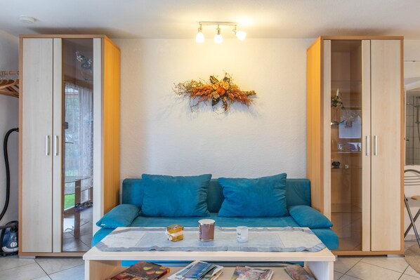 Una habitación con un sofá, una mesa con una vela y un adorno en la pared.