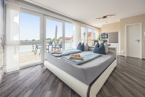 Una habitación moderna con una cama grande, un balcón con vistas y una kitchenette.