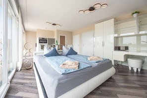 A modern bedroom with a large bed, a desk, and a view of the city.