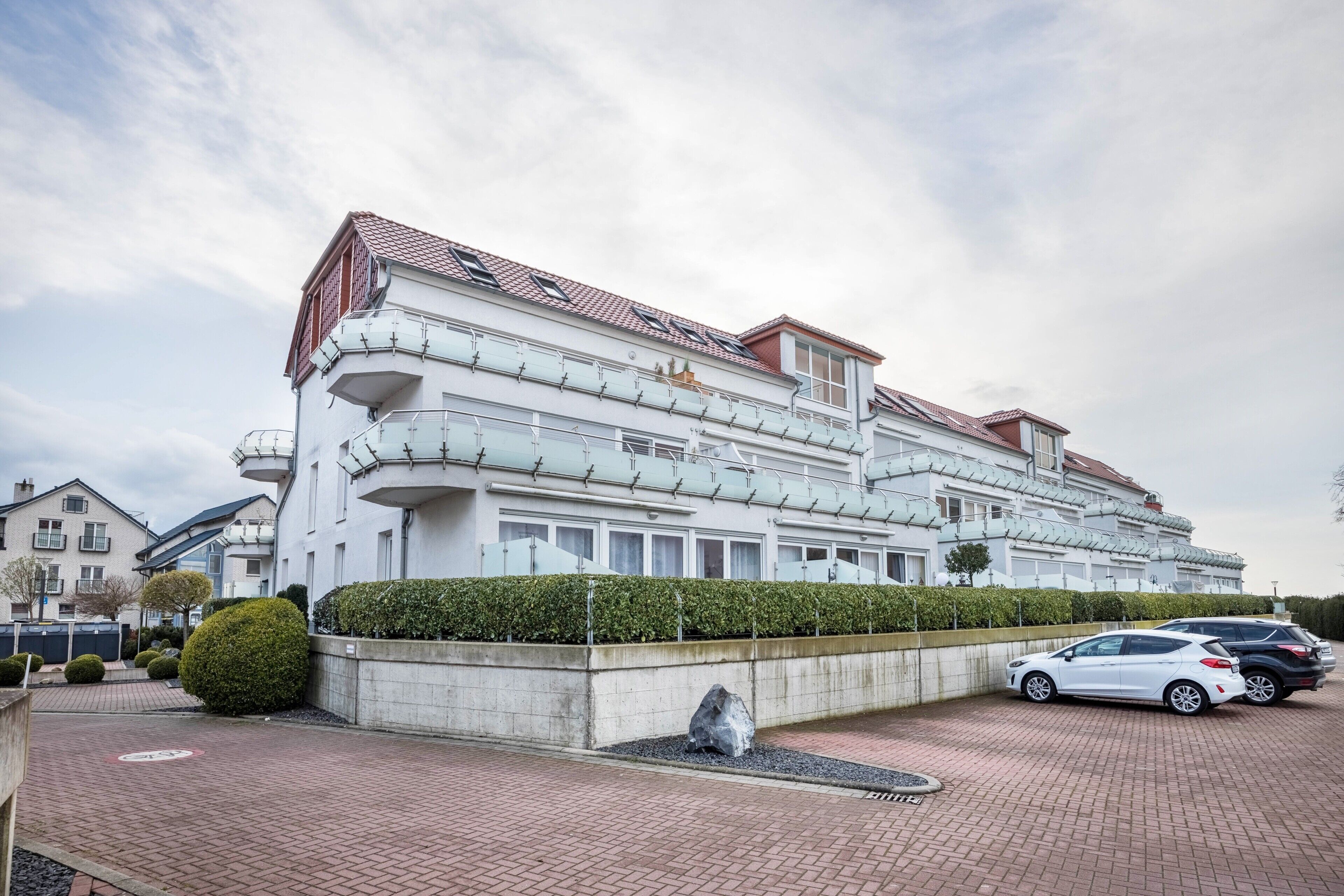 Un hôtel à plusieurs étages doté de balcons, d’un parking et d’un jardin aménagé.