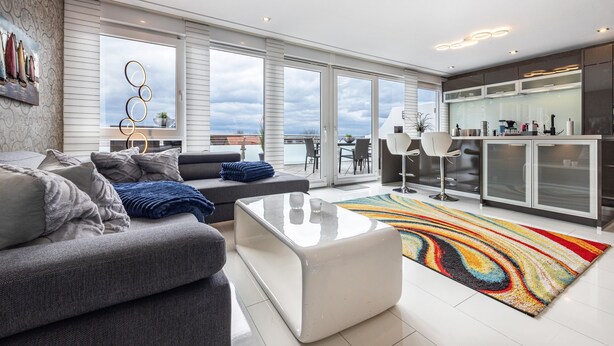 A modern living room with a sofa, a coffee table, and a colorful rug. - Apartment 'Studio Comfort' with direct Lake View, Balcony and Wi-Fi (Steinhude)
