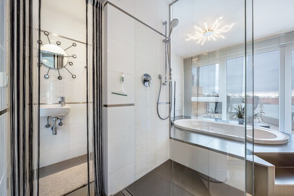 Un baño moderno con cabina de ducha de vidrio, un espejo grande y un lavabo integrado.