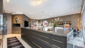 A modern kitchen with dark cabinetry, a central island, and a built-in TV. - Apartment 'Studio Comfort' with direct Lake View, Balcony and Wi-Fi (Steinhude)
