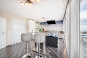 Een moderne keuken met een bar, een flatscreen televisie en uitzicht op het strand.