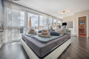 Quarto moderno com uma cama grande, uma TV e vista para a cidade.