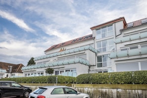 Um edifício residencial com vários andares, teto plano, janelas grandes e uma varanda visível.