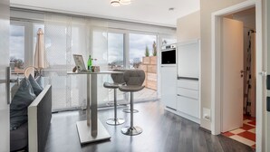 A modern kitchen with a dining area, large windows, and a view of the outdoors.