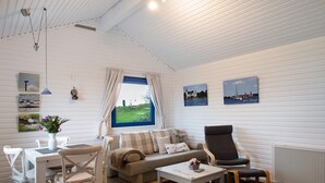 Una habitación acogedora con una mesa de comedor, sillas, un sofá, una mesa baja y una ventana con cortinas.