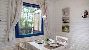 Un comedor con una mesa dispuesta para cuatro, una ventana con cortinas y obras de arte colgadas en la pared.