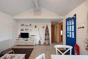 Una habitación acogedora con detalles de madera blanca, una puerta azul, un mueble blanco para la televisión y una chimenea.