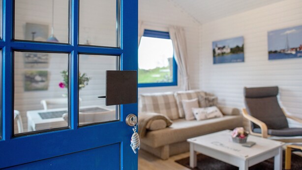 Una habitación con puerta azul, un sofá, una silla y una mesita de centro.