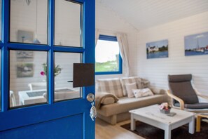 Une pièce avec une porte bleue, un canapé, un fauteuil et une table basse.