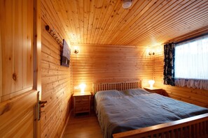 Una habitación con paneles de madera, una cama, lámparas de noche y una ventana con cortinas.