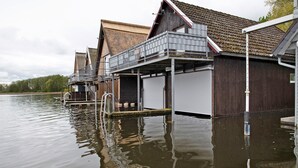 Ein Wohnhaus direkt am Wasser mit Anlegesteg, überdachtem Außenbereich und einem Gebäude mit Satteldach.