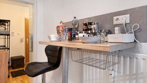 A kitchenette with a countertop, a chair, a bowl, a water bottle, and various kitchen appliances. - Apartment 'Blackforest Perla' – Cozy Flat with Indoor Pool, Private Terrace, Fast Wi-Fi (Höchenschwand)