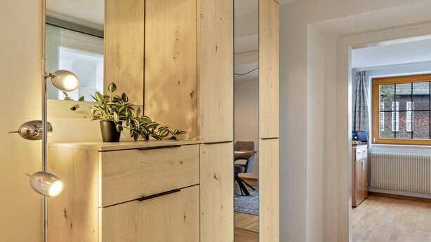 Una habitación con un armario de madera, un escritorio, una silla, un radiador y una ventana con cortinas.