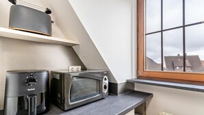 Una cocina con microondas, tostadora y ventana con vistas a edificios.