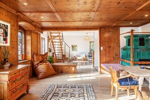 Un interior de madera con una escalera, un comedor y una vista a través de un ventanal abierto.
