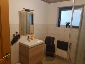 A bathroom with a sink, mirror, towel rack, and a window with a view.