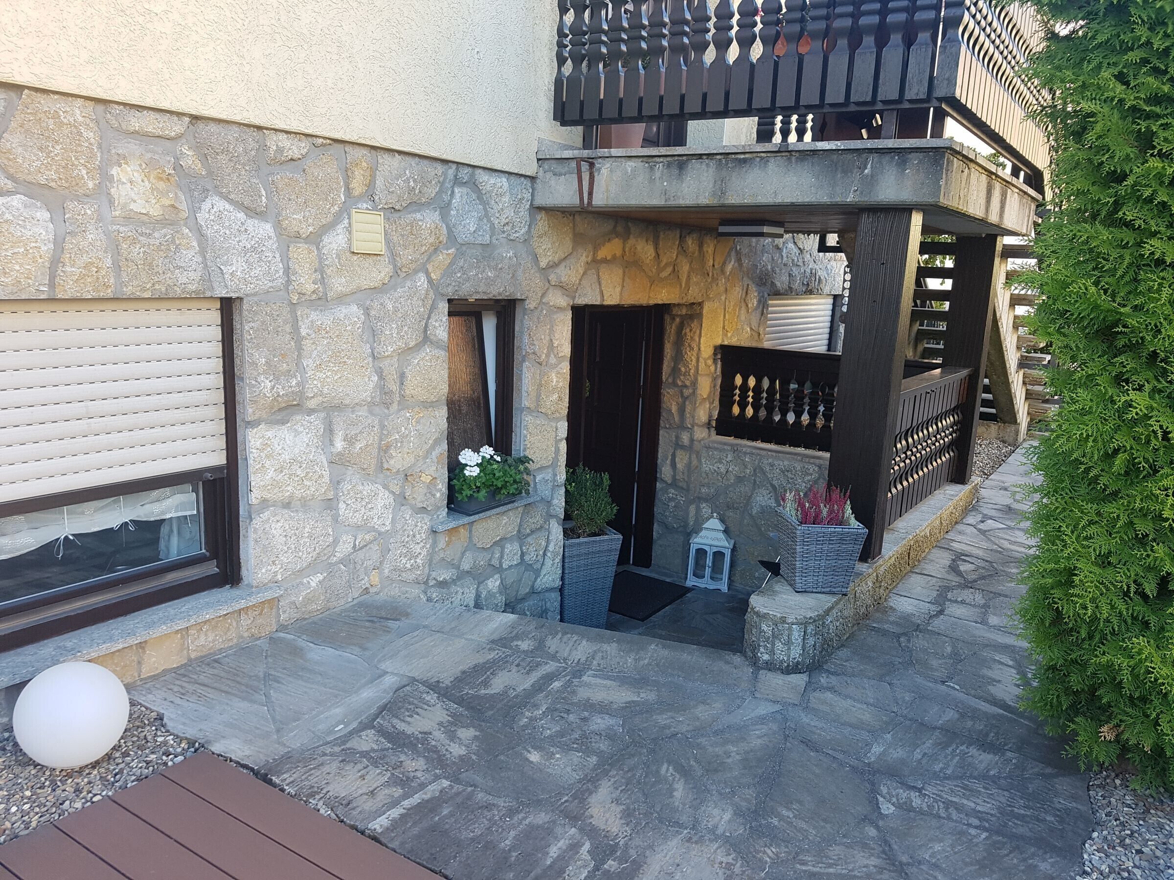 Un edificio in pietra con un balcone, una finestra con una pianta e un lampione.