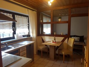 A compact kitchen with a sink, stove, and dining area with chairs and a table.