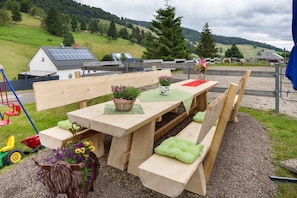 Une table de pique-nique en bois, avec des bancs, entourée d’une zone recouverte de gravier, agrémentée d’une tête de taureau décorative et de fleurs.