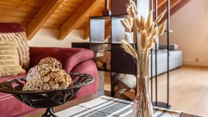 A cozy room with a wooden ceiling, a red sofa, a black metal table, and a vase with dried plants.