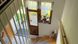 A staircase with a handrail, a door with a window, and a view of the outdoors.