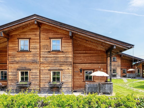 Traditional building with a central entrance and flanked windows, set amidst a well-maintained lawn and wooden fence.