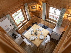 Cozy cabin kitchen with modern stove, small refrigerator, and dining area for four.