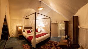 Ein Himmelbett mit Baldachin, ein Nachttisch, eine Lampe und ein kleiner Tisch mit Wasserkocher und Tasse.