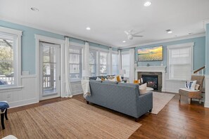 Un salón amplio con chimenea, ventanas grandes y ventilador de techo.