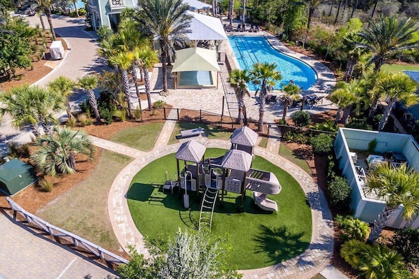 Un complejo turístico con piscina, zona de juegos para niños y área de descanso cubierta.