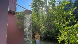Un jardin agrémenté d’un élément aquatique, un chapeau accroché à un arbre et un bâtiment en arrière-plan.