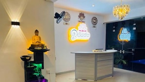 A reception desk with a neon sign, a Buddha statue, and a water feature. - Ismattha hotel  (Anuradhapura)