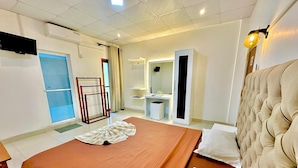 A hotel room with a bed, a wardrobe, a mirror, a small desk, and a bathroom. - Ismattha hotel  (Anuradhapura)