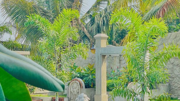 A poolside area with a wooden bench, a statue, and a stone wall. - Ismattha hotel  (Anuradhapura)