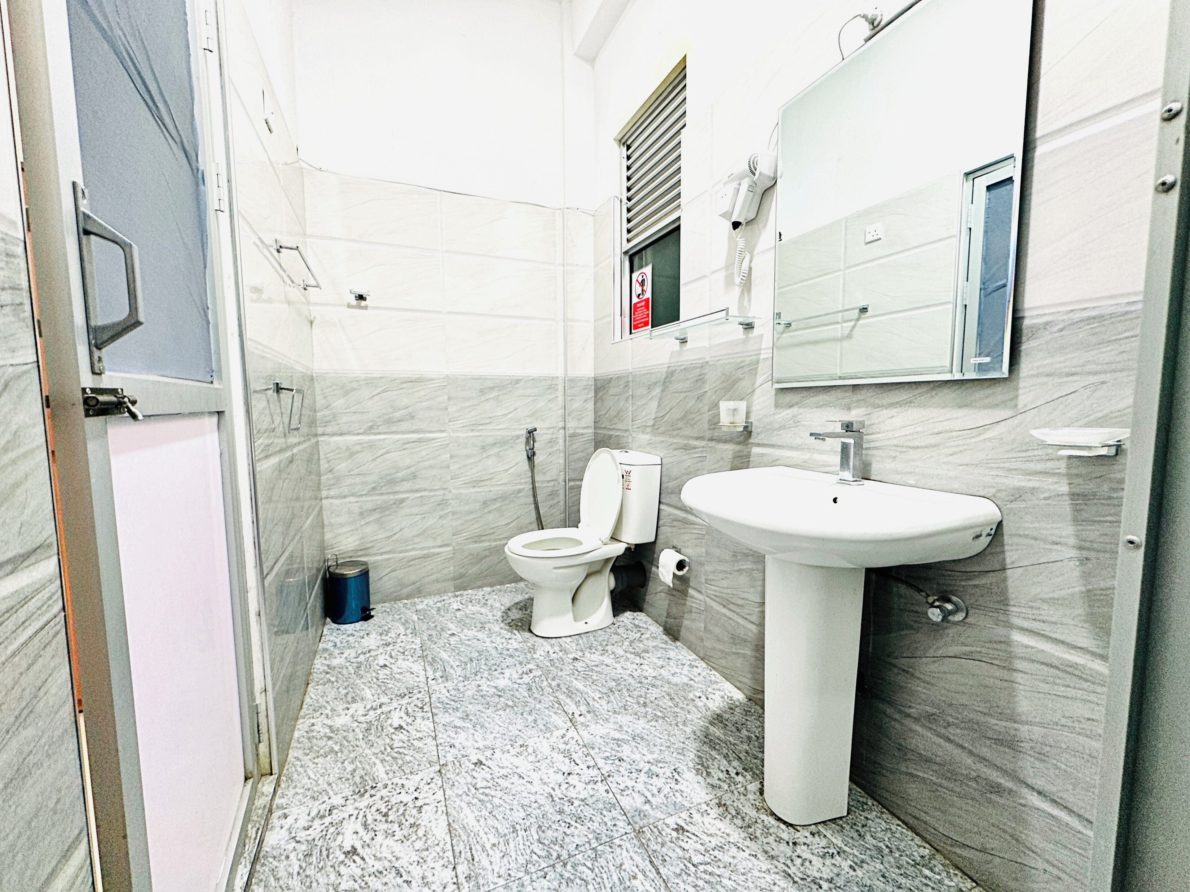 A bathroom with a toilet, sink, and mirror.