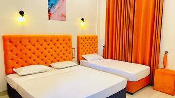 A room with two beds, each with an orange headboard, white bedding, and a small orange ottoman.