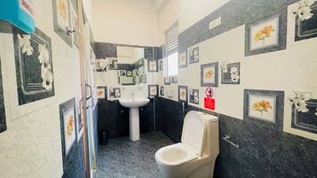 Un baño con inodoro, lavabo y espejo. Las paredes están decoradas con cuadros de flores.