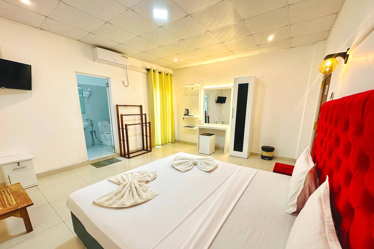 Een hotelkamer met een bed, een bureau, een stoel, een televisie en een badkamer zichtbaar door een geopende deur.