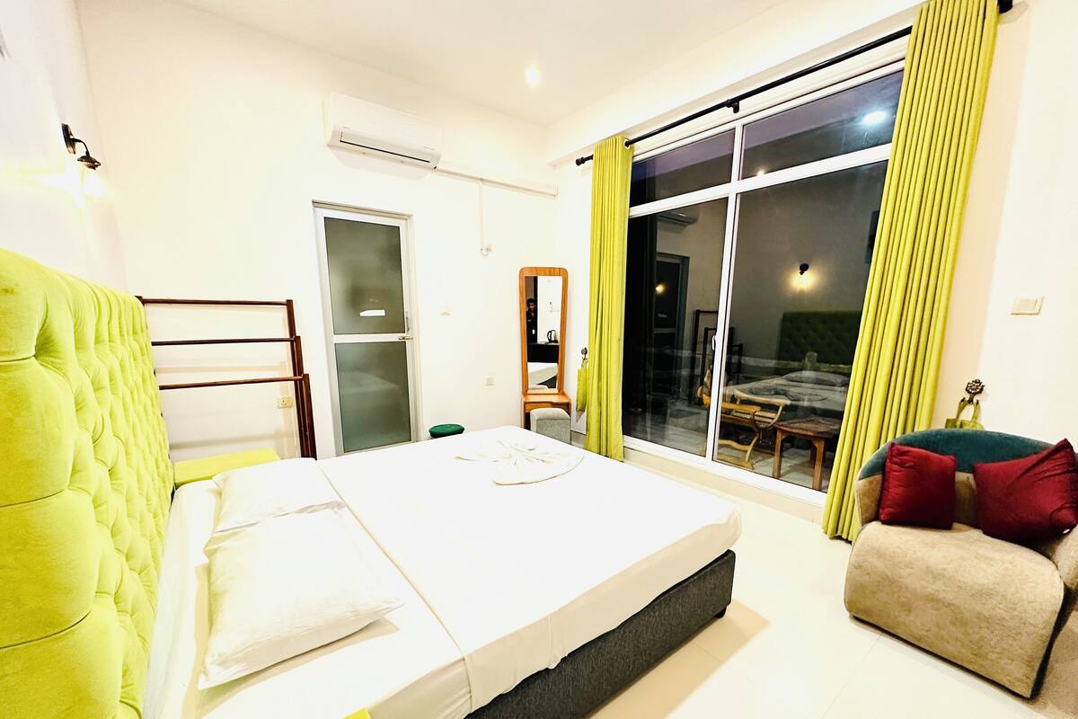 Een moderne slaapkamer met een bed, een stoel, een bank en een schuifdeur naar een balkon.
