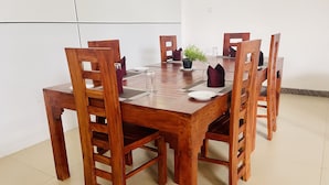 A wooden dining table with six chairs, a potted plant, and a glass vase. - Ismattha hotel  (Anuradhapura)