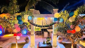 An outdoor wedding setup with a fountain, floral arrangements, and a table with a red tablecloth. - Ismattha hotel  (Anuradhapura)