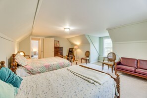 Ein Schlafzimmer mit zwei Betten, einer hölzernen Kommode, einem roten Ledersofa und einem Sessel.
