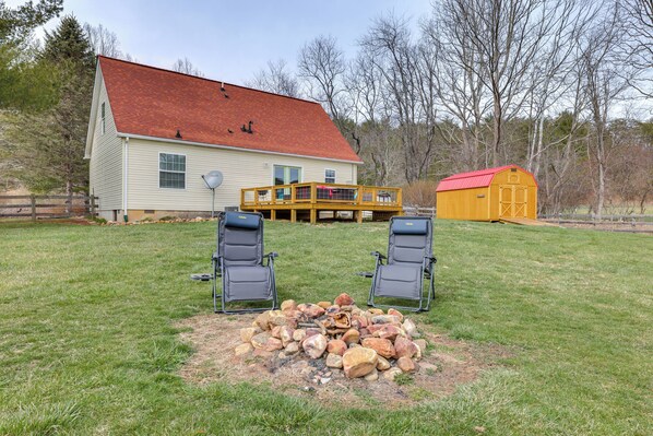 Ein Haus mit rotem Dach, einer Terrasse und einer Feuerstelle mit Steinen.